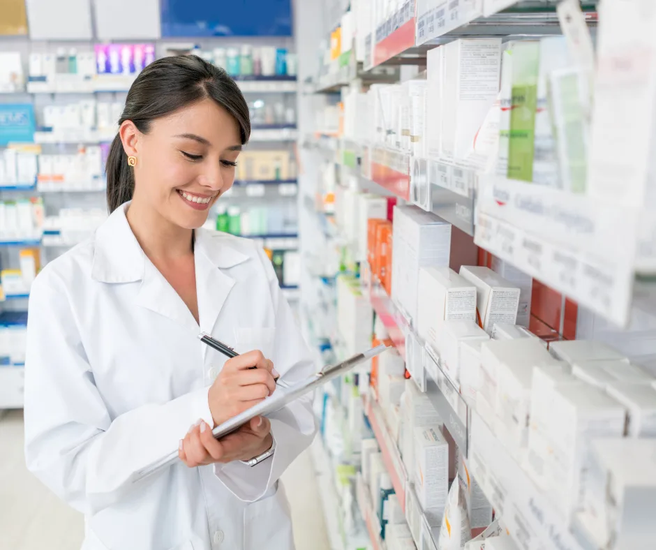 Pharmaassistentin in weissem Kittel prüft Medikamente im Apothekenregal